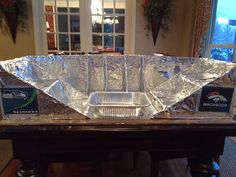 an aluminum foil covered dish sitting on top of a wooden table