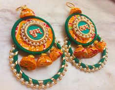 two pairs of colorful earrings on a marble counter top with beads and chains around them