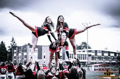 two cheerleaders are on top of each other in the middle of a football game