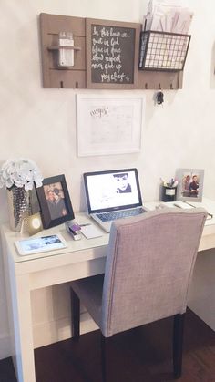 a laptop computer sitting on top of a white desk next to a wooden framed sign