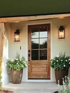 two large planters are on the outside of a house with an entry door and windows