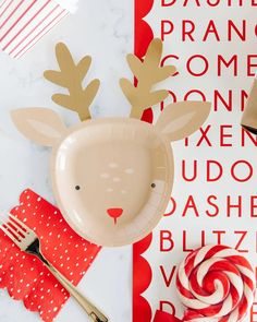 a paper plate with a reindeer face on it next to candy canes and napkins