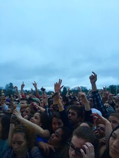 a large group of people standing around each other with their hands up in the air