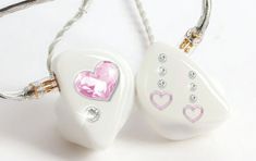 two white heart shaped pendants with pink hearts on them