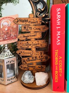 a wooden sign sitting on top of a table next to books and a candle holder