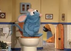 a blue stuffed animal sitting on top of a toilet