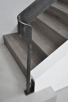 a metal handrail on the side of a wooden stair case next to a white wall