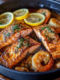 salmon and shrimp in a skillet with lemon wedges