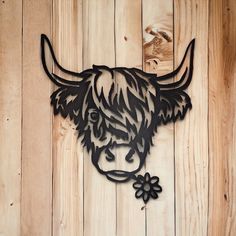 a metal cow head mounted on a wooden wall with a flower in it's ear