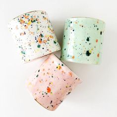 three different colored sprinkles are on the same coffee cup, one is pink and one is green