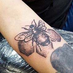 a man with a tattoo on his arm has a bee and flower design on it