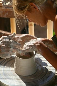 a woman is making clay on a wheel