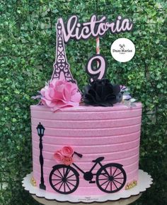 a pink cake with the eiffel tower in the background and flowers on top