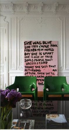 a living room with green chairs and a pink sign on the wall above it that says she was blue