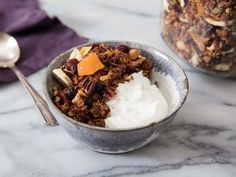 a bowl filled with granola and yogurt on top of a marble counter