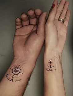 two hands holding each other with tattoos on them