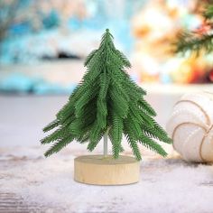 a small christmas tree sitting on top of a wooden stand next to a ball of yarn