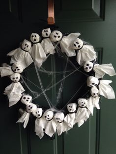 a wreath decorated with fake ghost heads and white paper bats is hanging on the front door