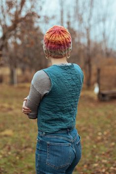 a person with a knitted hat on standing in the grass and looking at something