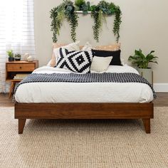 a bed with pillows and plants on the headboard, along with two nightstands