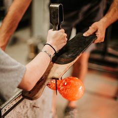 two people working on an object in a room with oranges and other things around them