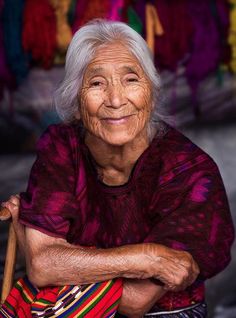 an old woman sitting on the ground with her arms crossed and looking at the camera