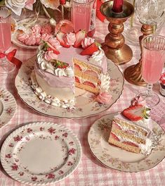 a table topped with plates and cakes covered in frosting next to pink flowers on top of a checkered table cloth