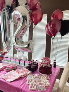 a pink table topped with lots of balloons and desserts next to a number twenty sign