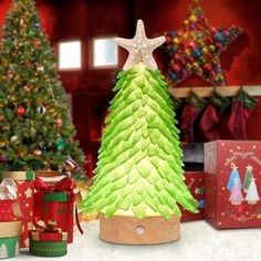 a christmas tree made out of paper and wrapped presents in front of a decorated christmas tree