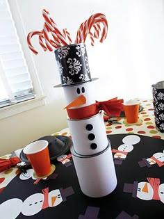 a snowman made out of toilet paper sitting on top of a table with candy canes