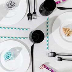 the table is set with black and white plates, silverware, and candy canes