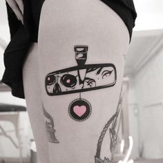 a woman's leg with tattoos on it and a camera in the middle of her thigh