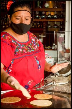 a woman wearing a black mask is making pancakes