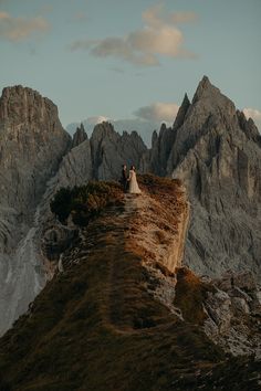 a bride and groom standing on top of a mountain