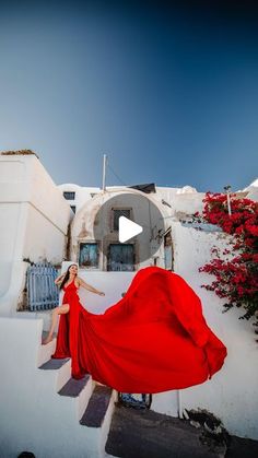 a woman in a red dress is standing on steps with her arms spread out to the side