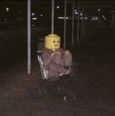 a person sitting in a shopping cart with a smiley face on it's head