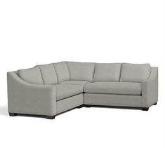 a gray sectional couch sitting on top of a white floor