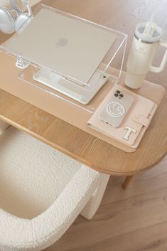 an apple laptop computer sitting on top of a wooden table next to a cup and other items