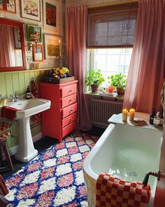 a bathroom with a bathtub, sink and red cabinet in it's center