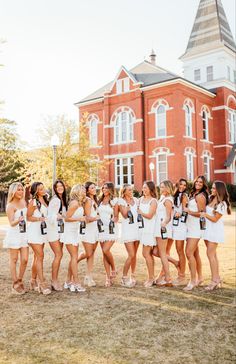 a group of women standing next to each other in front of a red brick building