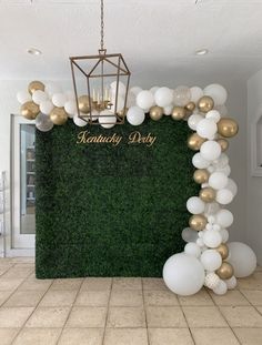 a green wall with white and gold balloons