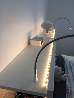 a white desk with some lights on it and a stuffed animal next to the table