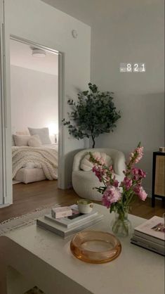 a living room filled with furniture and flowers on top of a coffee table in front of a bed