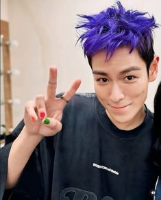 a young man with purple hair making the peace sign