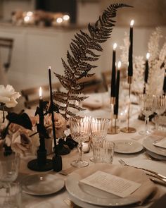 the table is set with candles, plates and silverware for an elegant wedding reception