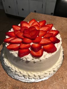 there is a cake with white frosting and fresh strawberries on the top it