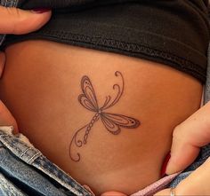 a woman's stomach with a dragonfly tattoo on it