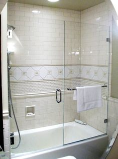 a bathroom with a glass shower door and white tile walls