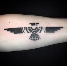 a black and white bird tattoo on the left arm with an arrow in it's center