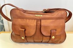 Samsonite Travel / Messenger Bag in brown with gold accents Adjustable shoulder strap Clear inside pocket for travel documents 2 external pockets with brass button closure Body is One large zipper compartment 4 plastic feet on bottom Previously owned by a Magician!! Perfect for overnight travel, business, laptop, beauty bag.  Vintage good condition - small stains on bottom of bag.  Not sure if it is authentic leather or faux leather **All vintage items are pre-owned and pre-used. These vintage c Gold Shoulder Bag With Brass Hardware For Travel, Brown Travel Satchel With Pockets, Brown Office Shoulder Bag With Pockets, Brown Shoulder Bag With Pockets For Office, Brown Shoulder Bag With Pockets For Trip, Travel Messenger Bag, Travel Documents, Business Laptop, Travel Business